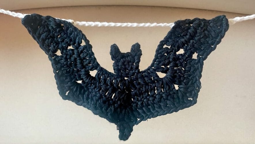 Bat keep its shape hanging in garland due to taut line of chains between wings above the head