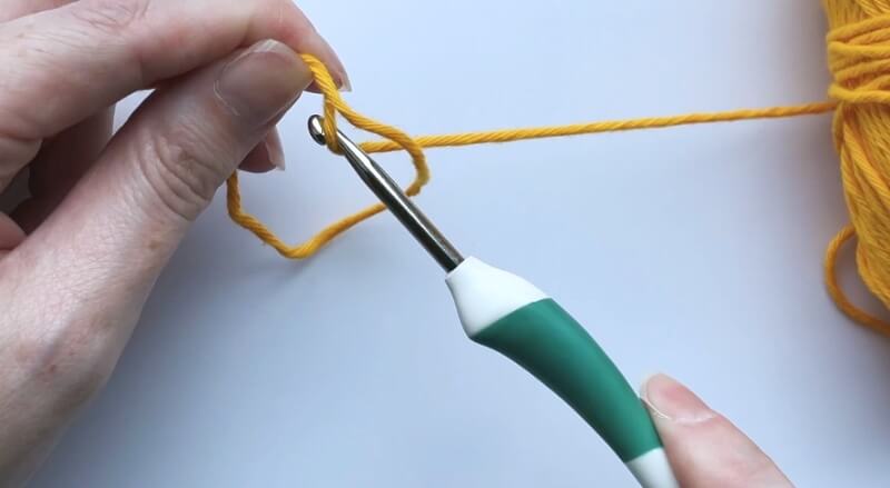 Put your crochet hook through the ring and pull through a loop from your yarn ball