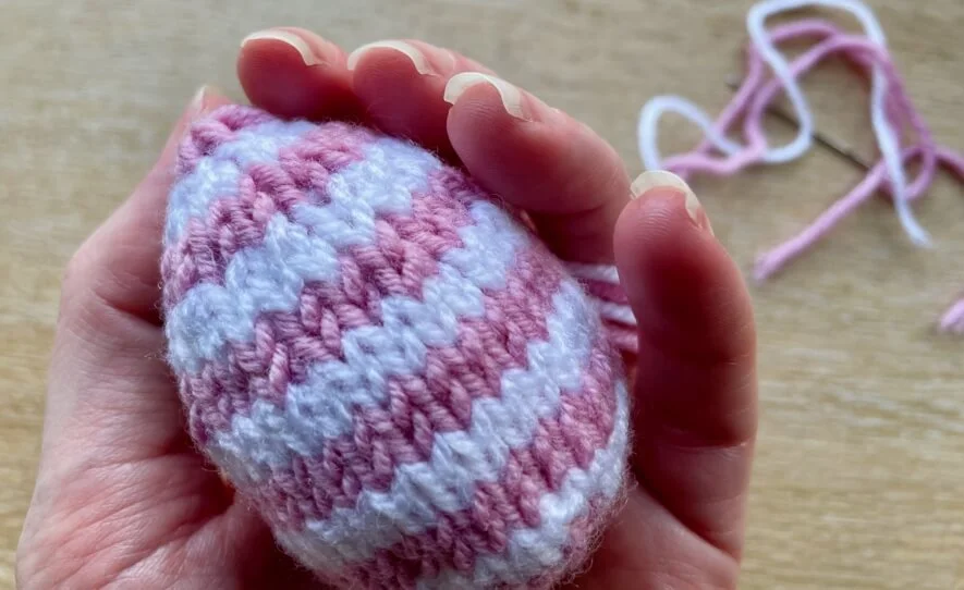 Flat knit striped easter egg in hand