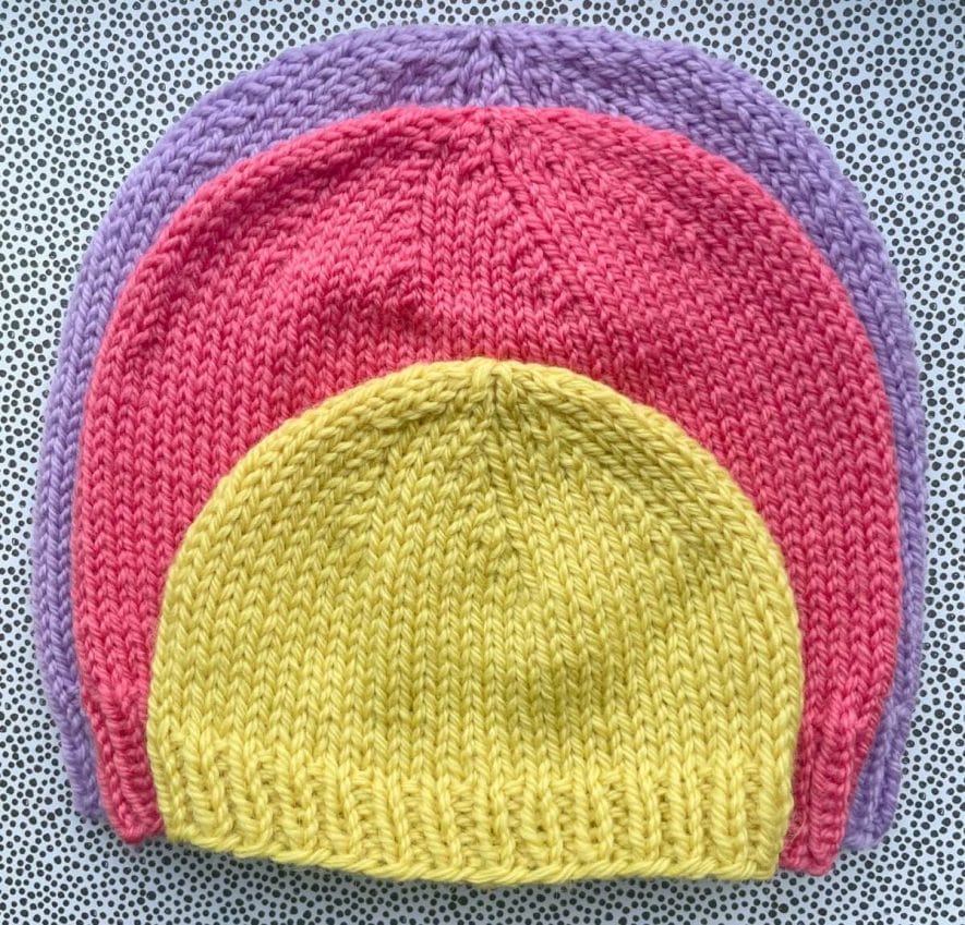 Baby knit hat on top of child hat on top of adult hat