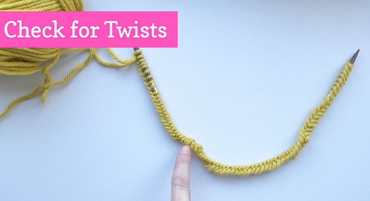 Finger pointing at twist in long tail cast on on circular knitting needle