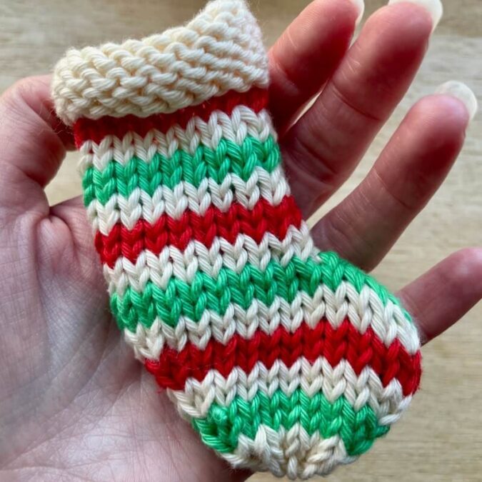 Striped mini stocking in cream, green and red cotton with purl cuff, knit flat on straight needles