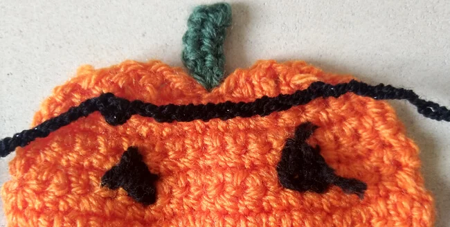 Back view of pumpkin post attachment showing garland chain on the left, chains added across pumpkin between attachment stitches and then garland chain continuing on the right.