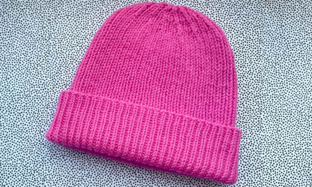 Free ribbed hat knitting pattern, shown in pink wool