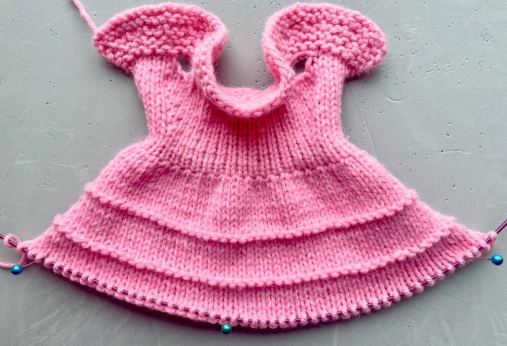 The knitted dress after row 28 before the bottom ruffle, with purl right side rows for 2 more ruffles